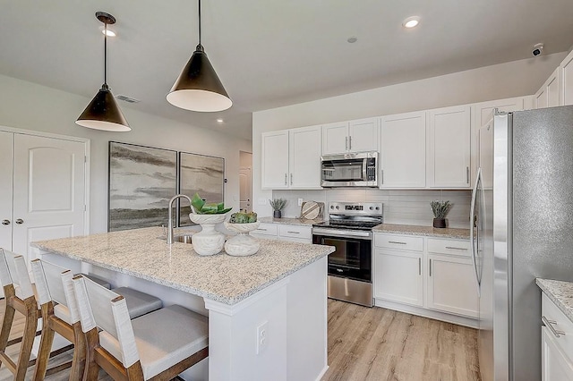 kitchen with white cabinets, tasteful backsplash, stainless steel appliances, and visible vents