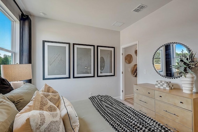 bedroom with baseboards, visible vents, and multiple windows