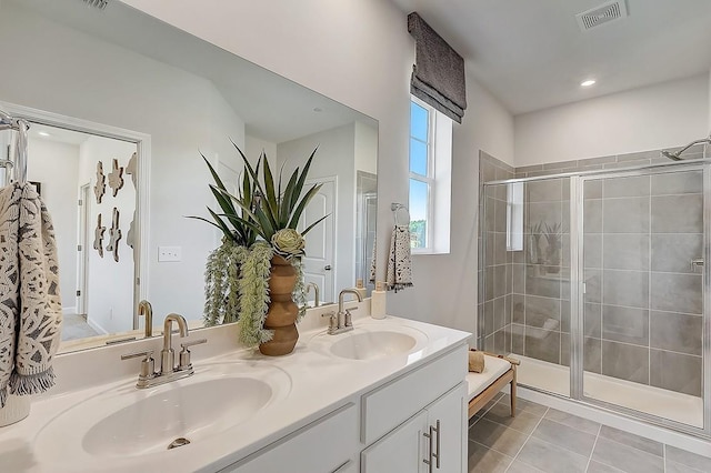 full bathroom with double vanity, visible vents, a stall shower, and a sink