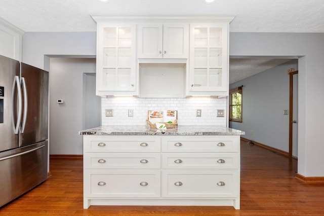 kitchen featuring stainless steel fridge with ice dispenser, backsplash, baseboards, glass insert cabinets, and a textured ceiling