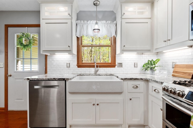 kitchen featuring white cabinets, stainless steel appliances, a sink, and backsplash