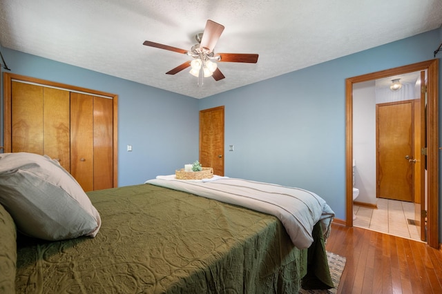 bedroom with a textured ceiling, ensuite bathroom, baseboards, a ceiling fan, and hardwood / wood-style flooring