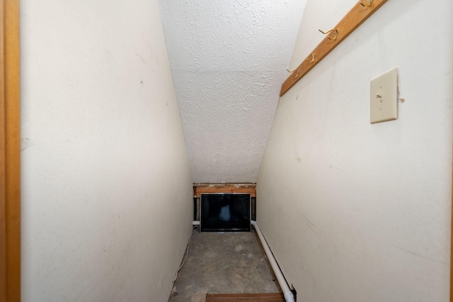 stairs featuring a baseboard radiator and unfinished concrete flooring