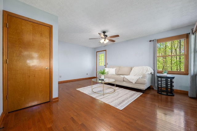 living area featuring wood finished floors, a ceiling fan, and baseboards