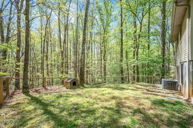 view of yard featuring a fenced backyard, a view of trees, and central AC