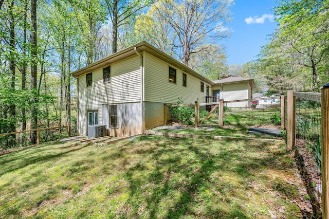 rear view of property featuring a lawn, central AC, and fence