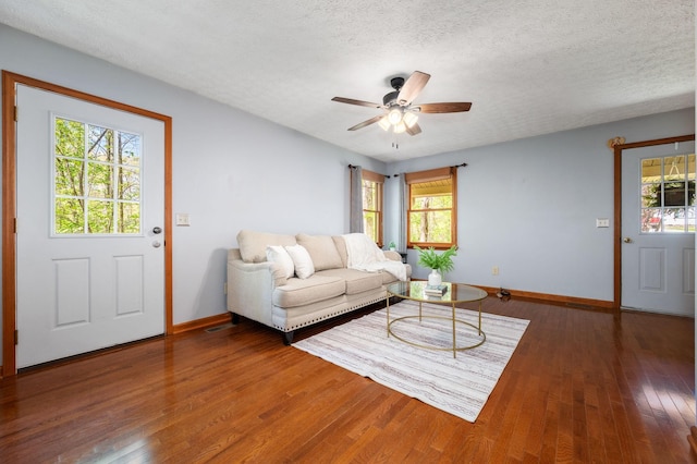 living room with ceiling fan, baseboards, and a wealth of natural light
