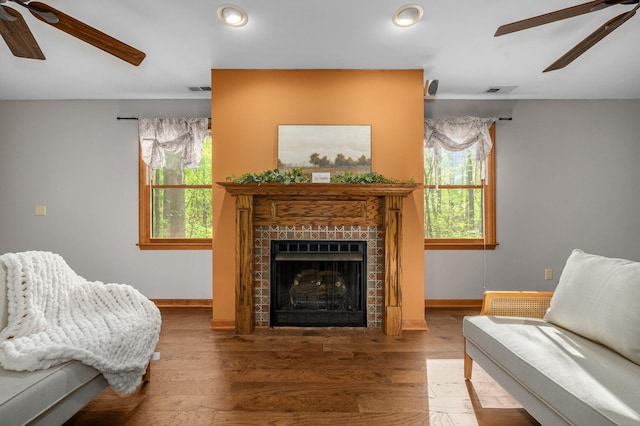 living area featuring visible vents, a tiled fireplace, baseboards, and ceiling fan