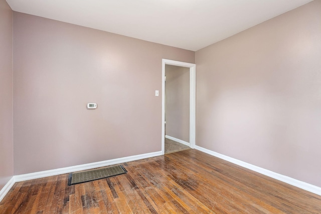 empty room with baseboards, wood finished floors, and visible vents