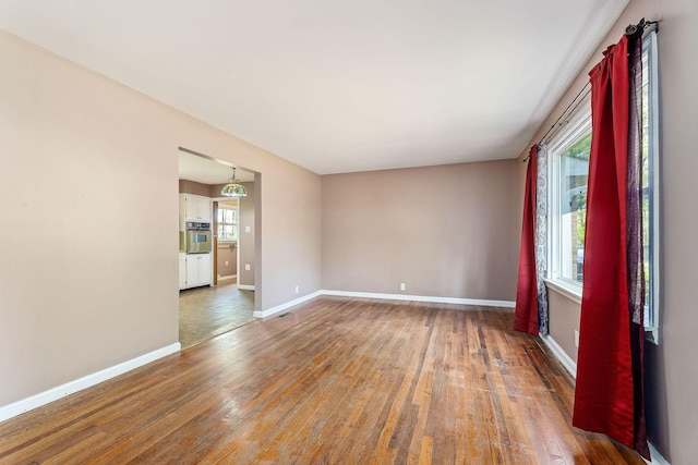 spare room featuring baseboards and wood finished floors