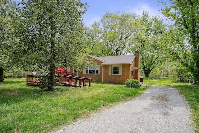 view of front of property with a wooden deck, driveway, brick siding, and a chimney