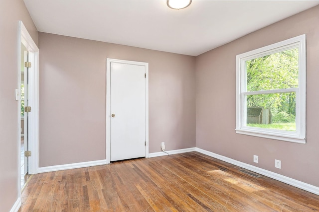 unfurnished room with baseboards, wood finished floors, and visible vents