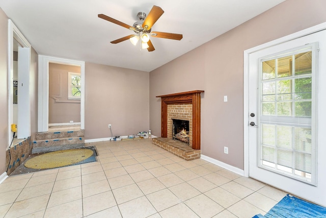 unfurnished living room with a healthy amount of sunlight, light tile patterned flooring, baseboards, a fireplace, and ceiling fan