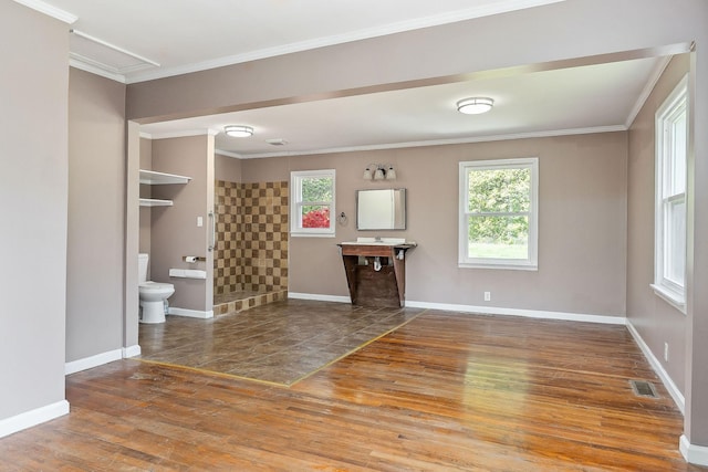 unfurnished living room featuring baseboards, wood finished floors, visible vents, and a wealth of natural light