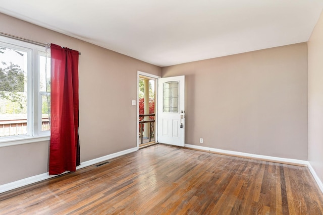 empty room featuring wood finished floors, visible vents, and baseboards