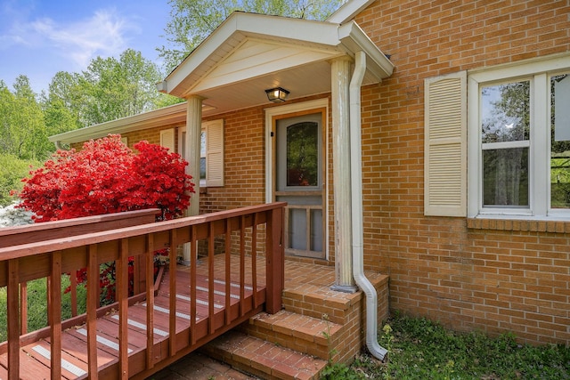 entrance to property featuring a wooden deck and brick siding