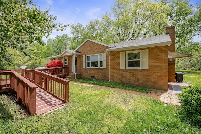 view of front of home with a chimney, brick siding, a front yard, and a deck