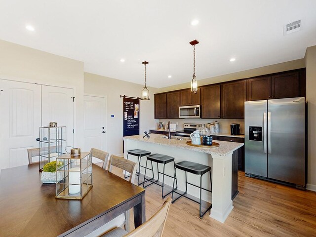 270 Subban Ct, Lebanon, TN 37087 - kitchen with an island with sink, stainless steel appliances, dark brown cabinets, visible vents, and light wood-type flooring