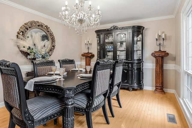 dining area with hardwood / wood-style floors, visible vents, ornamental molding, baseboards, and a notable chandelier