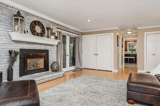 living room featuring wood finished floors, a brick fireplace, baseboards, and ornamental molding