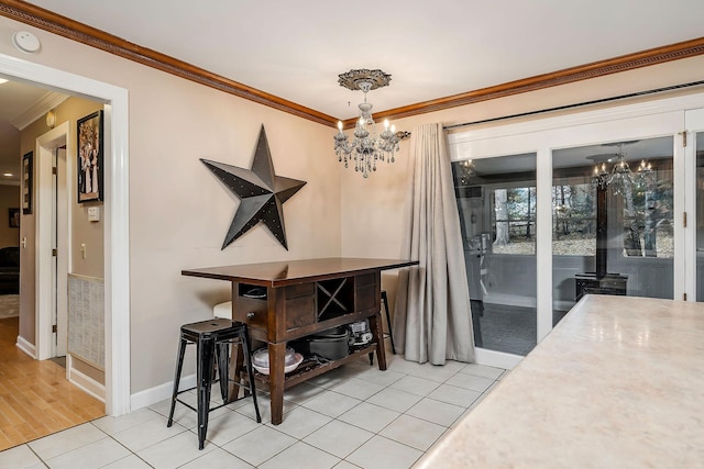dining space with a chandelier, crown molding, baseboards, and light tile patterned floors