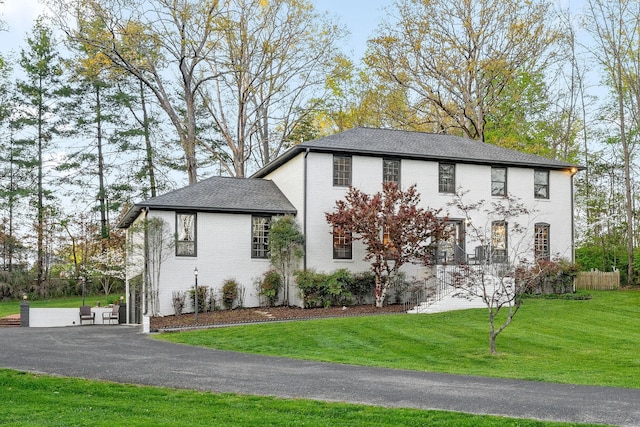 colonial house featuring a front lawn and brick siding