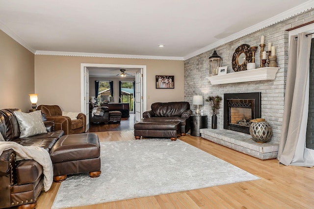 living room with a fireplace, a ceiling fan, hardwood / wood-style flooring, and ornamental molding