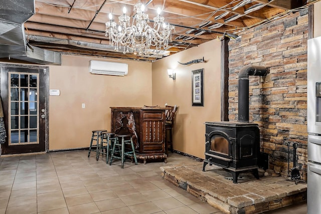 basement featuring tile patterned floors, baseboards, a notable chandelier, a wall mounted AC, and a wood stove