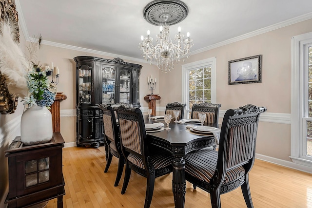 dining area with an inviting chandelier, crown molding, light wood finished floors, and baseboards