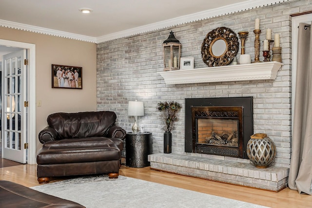 living area featuring crown molding, a brick fireplace, and wood finished floors