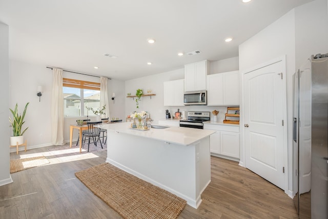 118 Olivia Cir, Chapel Hill, TN 37034 - kitchen with stainless steel appliances, white cabinets, light countertops, a center island with sink, and light wood-style flooring