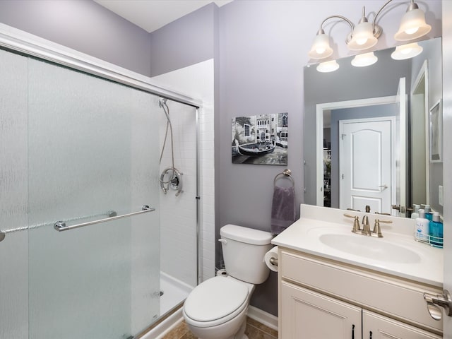 bathroom with baseboards, vanity, toilet, and a stall shower