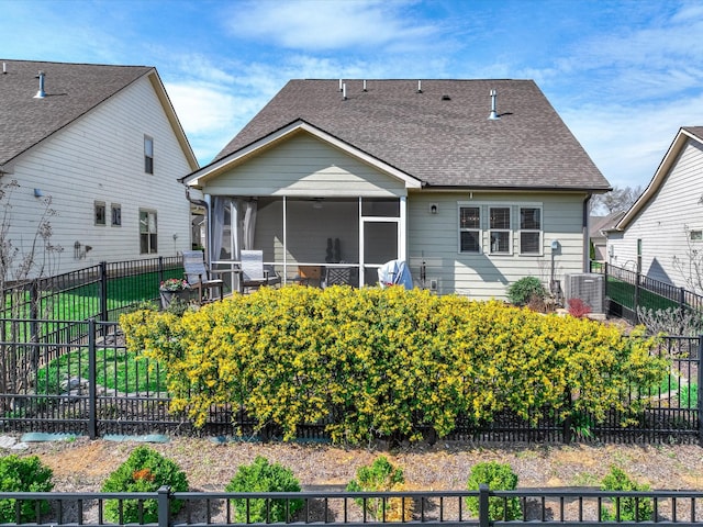 rear view of house featuring a fenced backyard, a shingled roof, a sunroom, and central AC unit