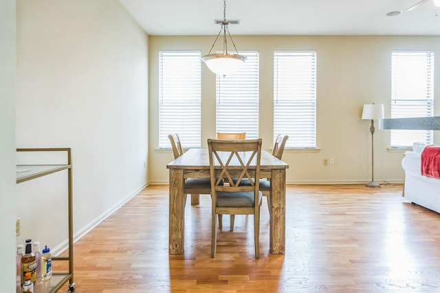 dining space featuring light wood-style flooring, baseboards, and plenty of natural light