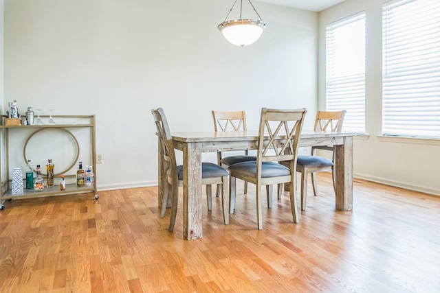 dining room with plenty of natural light, light wood finished floors, and baseboards
