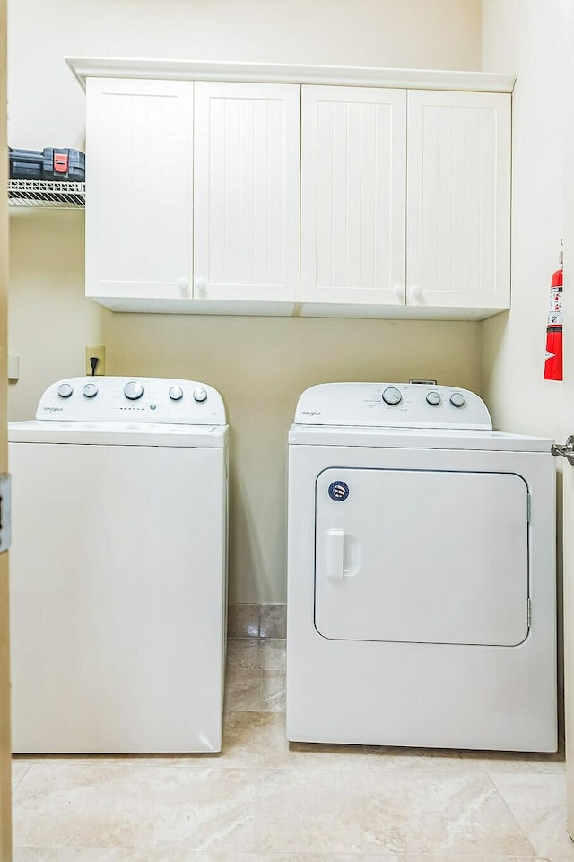 clothes washing area featuring cabinet space and independent washer and dryer