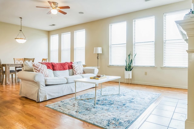 living area with baseboards, a ceiling fan, visible vents, and light wood-type flooring