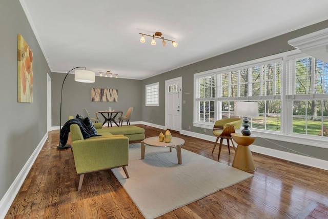 living area with wood finished floors, visible vents, baseboards, and ornamental molding