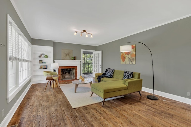 living room with baseboards, wood finished floors, a fireplace, and ornamental molding