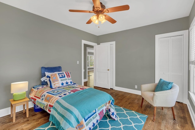 bedroom featuring baseboards, multiple closets, wood finished floors, and a ceiling fan