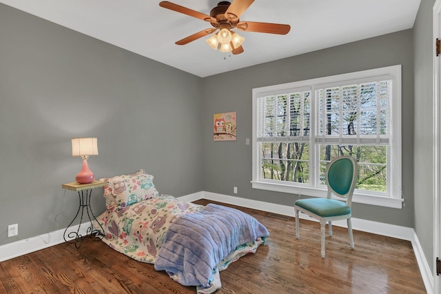 bedroom with wood finished floors, baseboards, and multiple windows