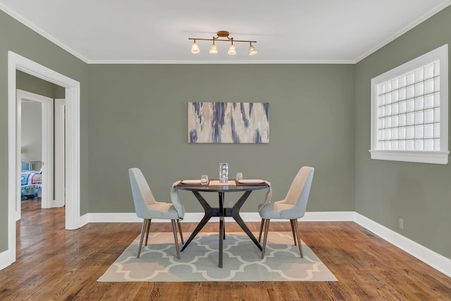 dining space with baseboards, crown molding, and wood finished floors