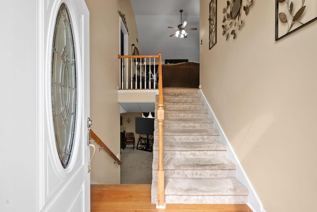 stairway with a ceiling fan and baseboards
