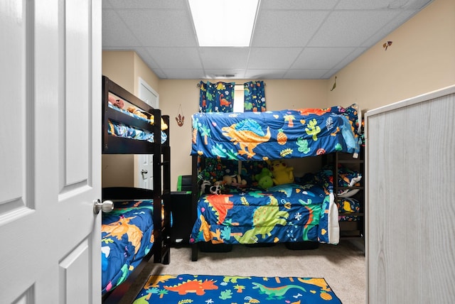 bedroom featuring carpet floors and a drop ceiling
