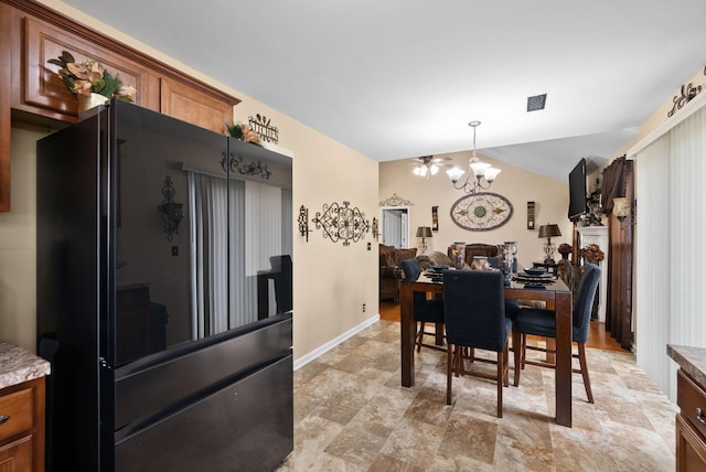 dining space featuring vaulted ceiling, an inviting chandelier, stone finish flooring, baseboards, and visible vents