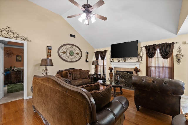 living area featuring a tile fireplace, high vaulted ceiling, visible vents, a ceiling fan, and hardwood / wood-style flooring