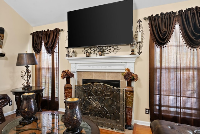 living room featuring lofted ceiling, baseboards, a tile fireplace, and wood finished floors