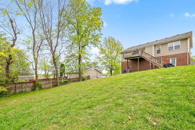 view of yard with a wooden deck, stairway, and fence