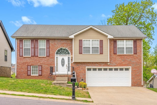 split foyer home featuring roof with shingles, driveway, brick siding, an attached garage, and a front yard