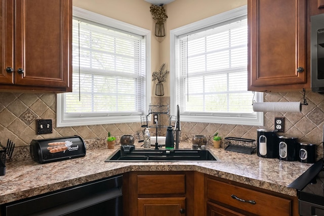 kitchen with backsplash, plenty of natural light, dishwashing machine, and a sink